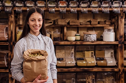 Woman holding brown paper bag of produce