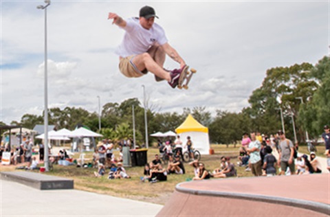 A young person at a skate park performing an aerial stunt.