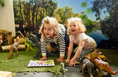 girls playing with dinosaurs in playground