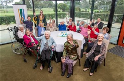 a group of centenarians at a table celebrating