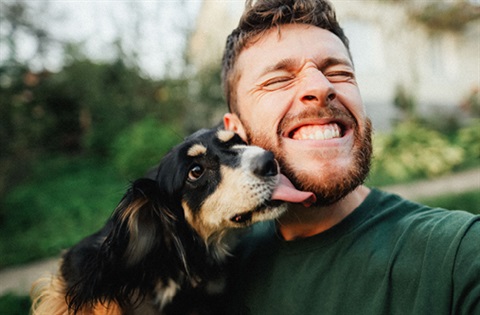 A man with a beard hugging a dog