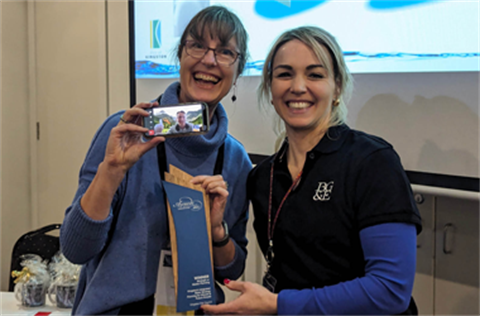 Two ladies smiling with an award