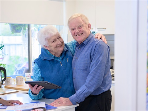 An older couple cuddle and smile