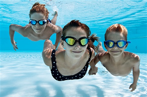 Three people with goggles swimming underwater.