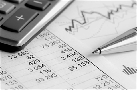 Columns of numbers on a printed spreadsheet with a calculator and pen sitting on top