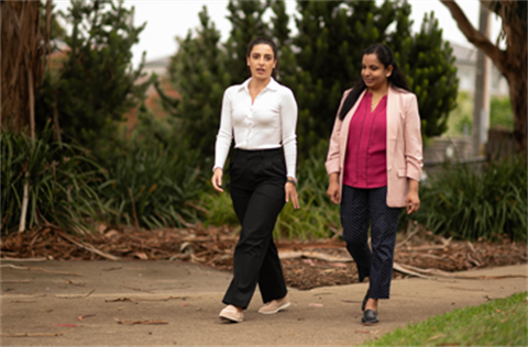 Two women walking and chatting on path.