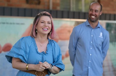 Woman smiling at camera with man in background..jpg