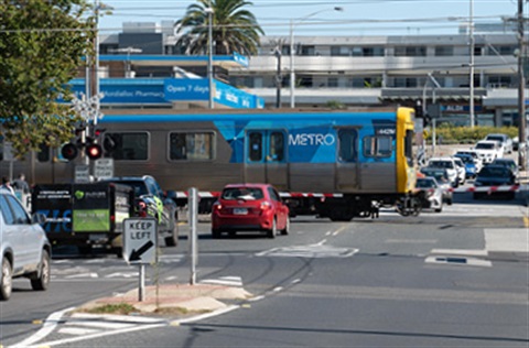 Cars stopped at the level crossing on McDonald Street in Mordialloc as a Metro train passes.