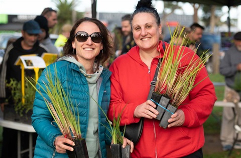 Two women holding plants.