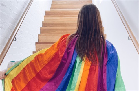 A woman displaying the Rainbow Flag.