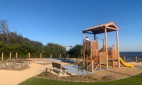 Wooden play structure with slide on the foreshore looking out into Port Phillip Bay. 