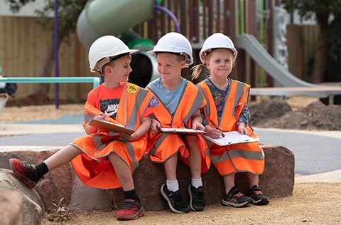 Three children at a playground dressed as inspectors