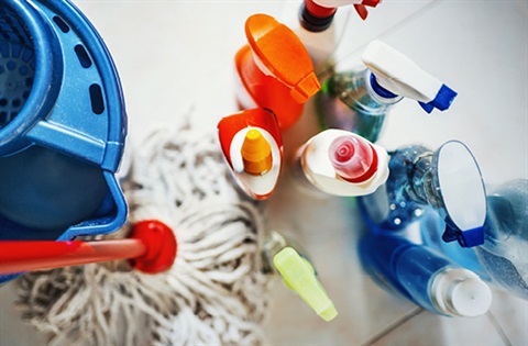A variety of cleaning products next to a mop and bucket.