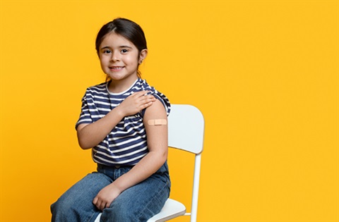 A smiling girl with a bandaid on her arm after having her immunisation shots.