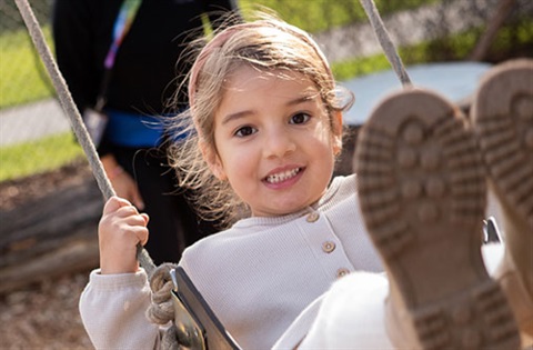 small girl jumping off a rock in a playground